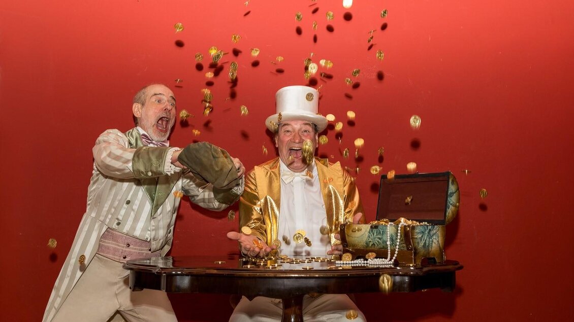 Zwei Schauspieler mit Geld und Schmuck an einem Tisch im Stück „Der Hochzeitstag“. | © Theater Absolut-Mario Maindl