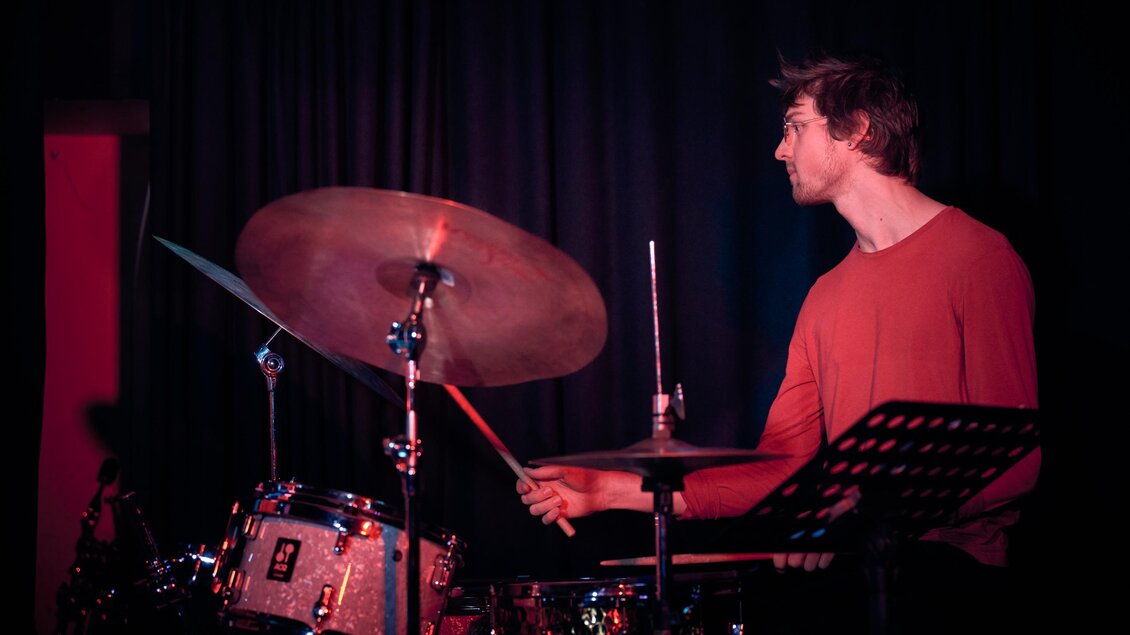 Junger Schlagzeuger mit Brille und rotem Pullover spielt beim Shortcut Festival in Graz am Schlagzeug. | © Kuro Simon