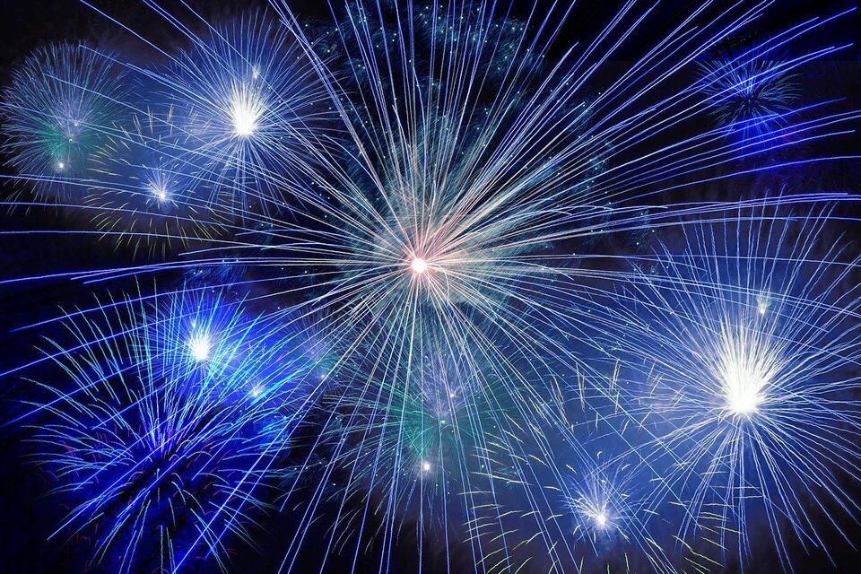 Ein spektakuläres Feuerwerk mit leuchtenden blauen und weißen Farben erhellt den Nachthimmel. Die Strahlen der Feuerwerkskörper strahlen in alle Richtungen und schaffen eine feierliche Atmosphäre. | © Pixabay.com