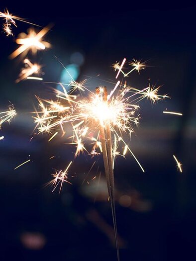 Ein leuchtender Feuerwerkskörper sprüht funkelnde Lichter in der Dunkelheit. Die Atmosphäre ist festlich und feierlich.