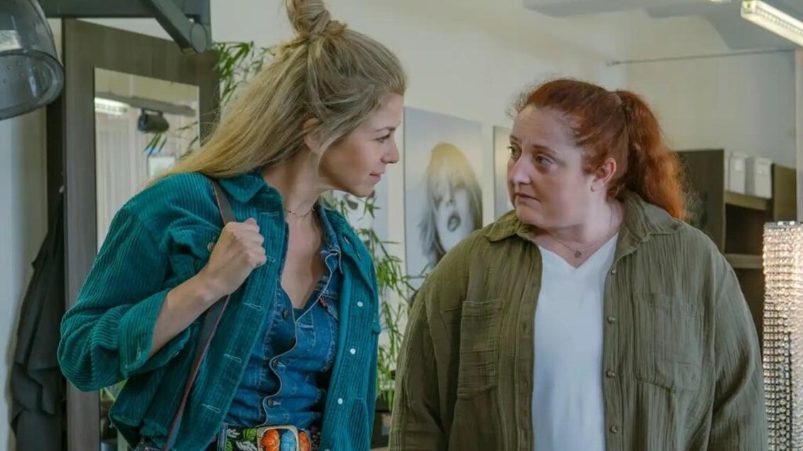 Zwei Frauen stehen in einem modernen Raum und unterhalten sich. Die eine trägt eine grüne Jacke und Jeans, während die andere ein weißes Oberteil und eine khakifarbene Jacke trägt. | © Oststeiermark Tourismus