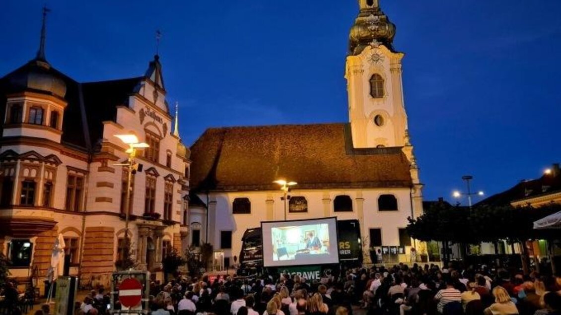 Eine große Menschenmenge sieht sich einen Film im Freien an. Im Hintergrund steht eine Kirchturm-Silhouette bei Nacht. | © Oststeiermark Tourismus