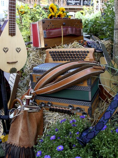 Various instruments of Styrian folk music, including accordion, string instruments, and double bass, arranged decoratively at the Styrian Singers' and Musicians' Meeting in Kalsdorf. | © Steiermark Tourismus-Michael Strobl