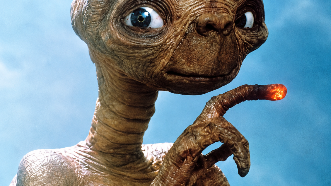Nahaufnahme von E.T., dem Außerirdischen, mit großen blauen Augen und erhobenem Finger mit leuchtender Spitze.  | © Flimmo