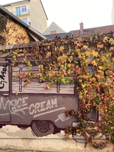 An artistic mural of an ice cream truck, surrounded by colorful ivy leaves. The inscription "SAVAGE CREAM" is displayed in bold lettering. | © (c) Graz Tourismus - Nadja Albrecht