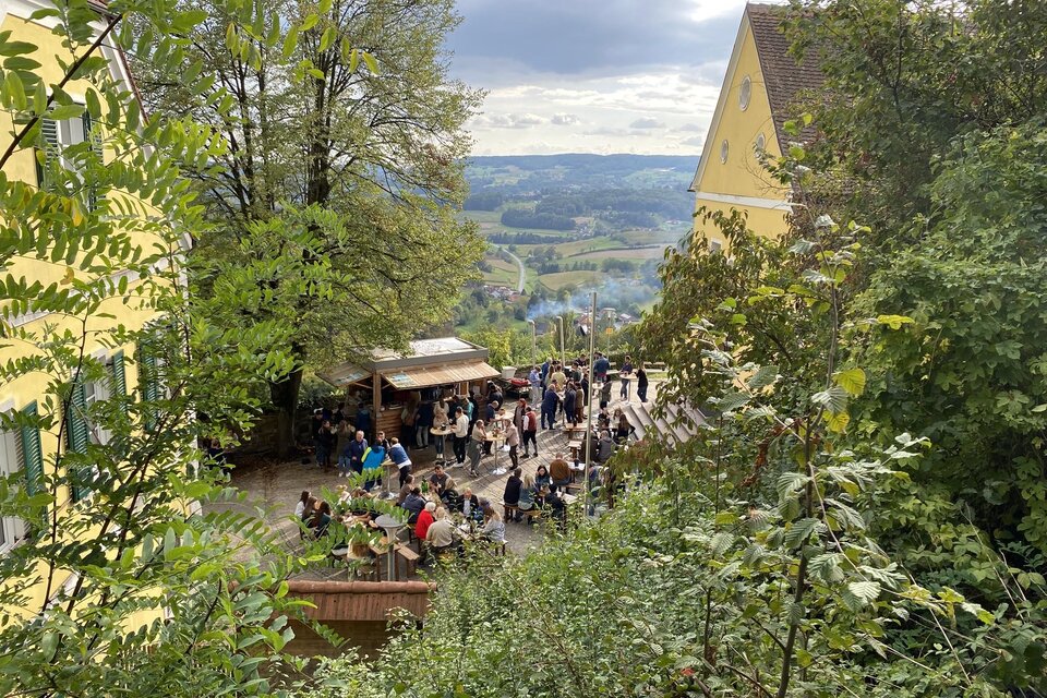 Stimmungsvolles Sturm-und-Kastanien-Fest im Burghof von Kapfenstein mit zahlreichen Gästen, gemütlichen Sitzplätzen und herrlichem Blick über die sanfte Hügellandschaft der Südoststeiermark – regionaler Genuss, geselliges Beisammensein und herbstliche Atmosphäre in der Erlebnisregion Thermen- & Vulkanland. | © Gemeinde Kapfenstein