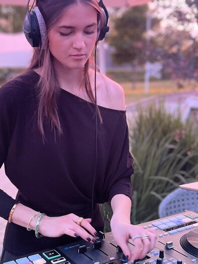 Eine DJane spielt Musik an einem Mischpult im Freien. Im Hintergrund sind einige Bäume und ein ruhiger Garten zu sehen. | © Kurkonditorei, Radkersburger Hof