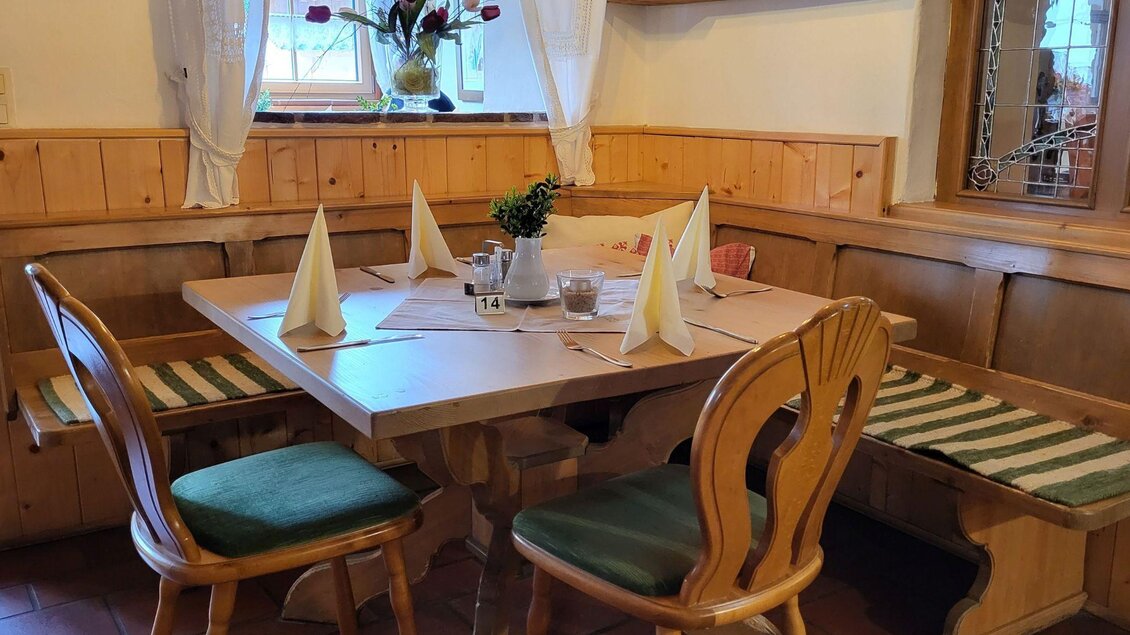 Der gemütliche Essbereich mit einem Holztisch und einladender Sitzecken. Die Dekoration ist einfach und einladend im Gasthof Berndl. | © Tourismusverband Ausseerland Salzkammergut