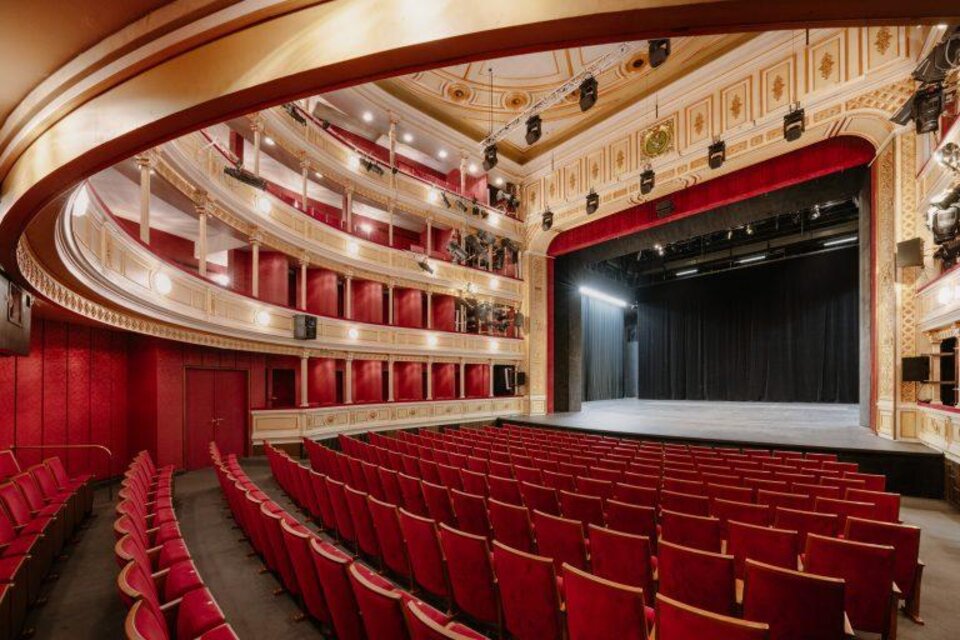 Ein elegantes Theater mit roten Sitzen und einer großen Bühne. Die geschwungene Architektur und die dekorativen Details schaffen eine einladende Atmosphäre. | © Lex Karelly