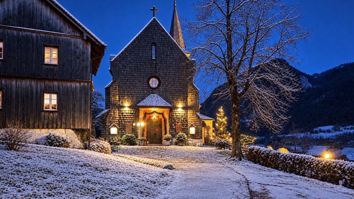 Eine charmante Kirche im Schnee, beleuchtet von warmem Licht. Die Umgebung ist malerisch mit schneebedeckten Bäumen und Bergen im Hintergrund. | © Bettina Scheck