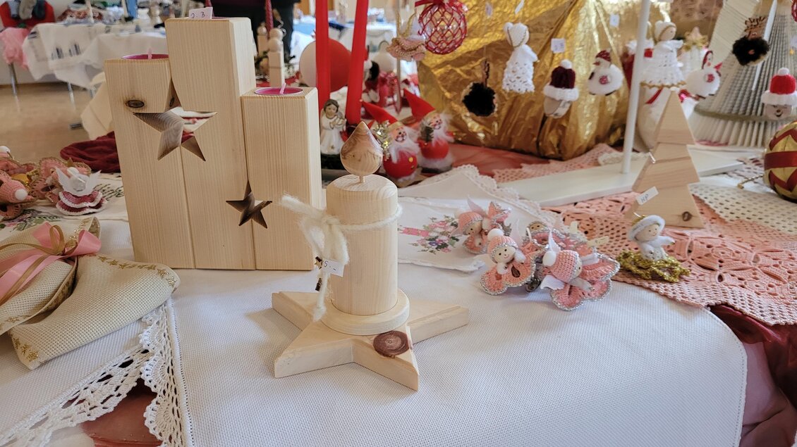 Eine festliche Tischdekoration mit Holzfiguren und handgefertigten Ornamenten. Verschiedene Kunsthandwerke und Geschenkartikel sind ebenfalls sichtbar. | © Susanne Greiner