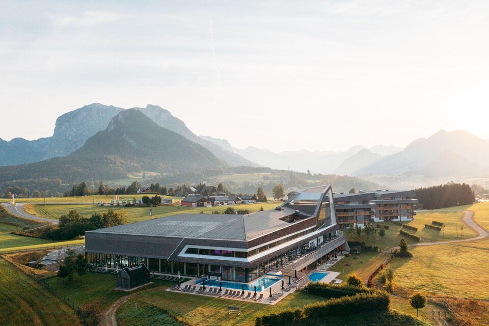 Ein modernes Gebäude in der Natur, umgeben von Bergen und Wiesen. Der Poolbereich ist gut sichtbar und die Landschaft strahlt Ruhe aus. | © Karl Steinegger