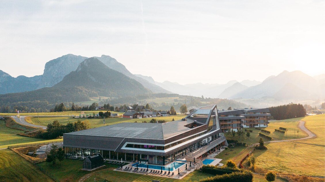 Ein modernes Gebäude in der Natur, umgeben von Bergen und Wiesen. Der Poolbereich ist gut sichtbar und die Landschaft strahlt Ruhe aus. | © Karl Steinegger