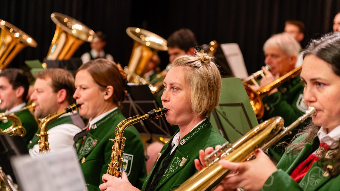 Eine Blaskapelle spielt auf der Bühne. Die Musiker tragen grüne Anzüge und konzentrieren sich auf ihre Instrumente. | © David Stocker