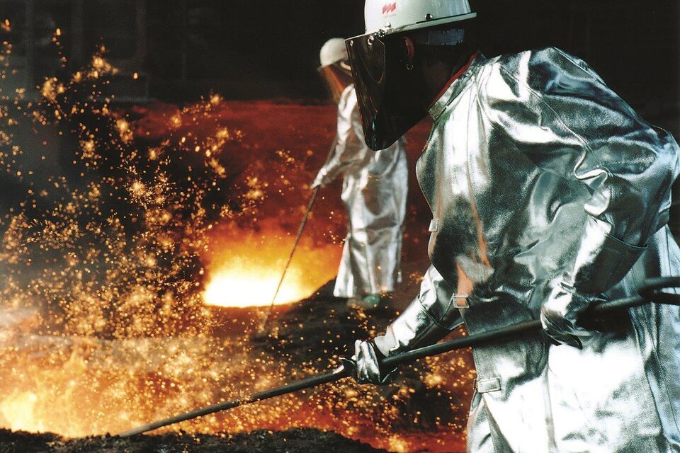 Arbeiter in Schutzkleidung stehen vor einem glühenden Schmelztiegel. Funken fliegen durch die Luft, während sie Metall bearbeiten. | © voestalpine