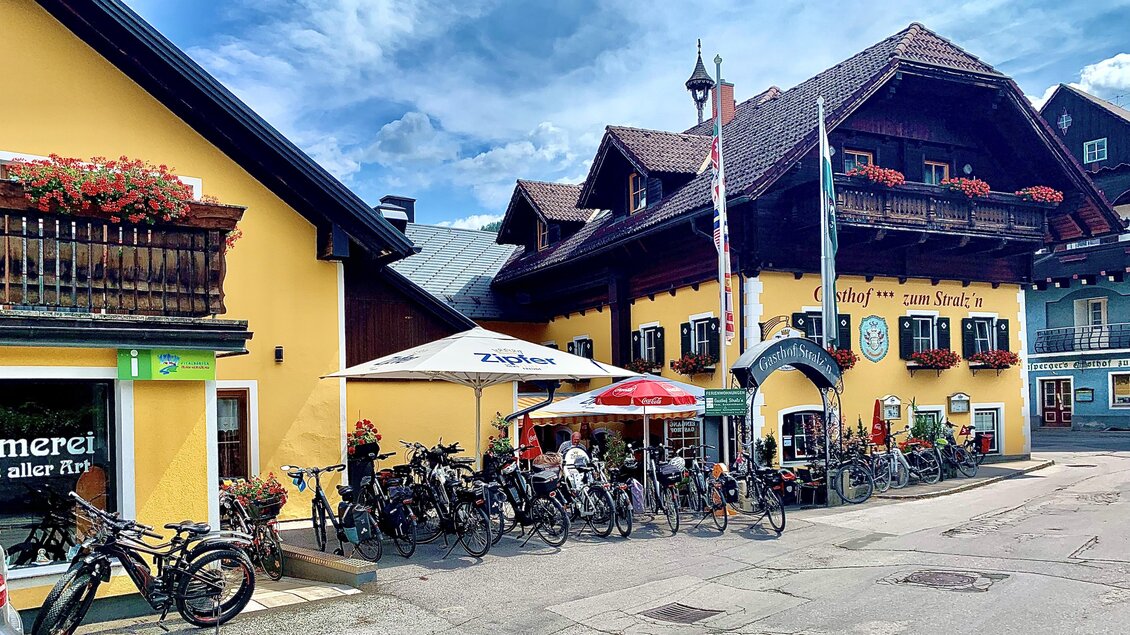 Ein traditionelles Gebäude mit gelber Fassade und Balkonen. Vor dem Haus stehen viele Fahrräder und Sonnenschirme laden zum Verweilen ein. | © Gerhard Schernthaner