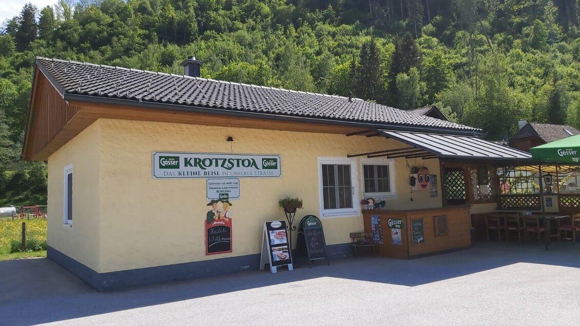 Ein gemütliches Gasthaus umgeben von grünen Hügeln. Draußen gibt es eine Terrasse mit Sitzgelegenheiten. | © Sabine Schweinberger