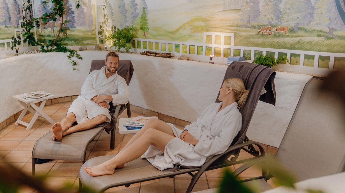 Ein gemütlicher Wellness-Bereich mit zwei Personen in Bademänteln. Sie entspannen auf Liegen und genießen die ruhige Atmosphäre. | © Christine Höflehner Photography