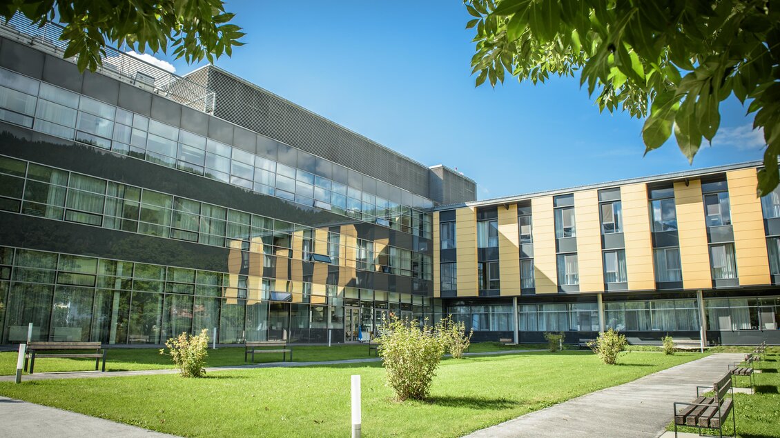 <p>Ein modernes Gebäude mit Glasfront und stilvollen Holzfassaden. Vor dem Gebäude ist eine grüne Wiese mit Pflanzen, der Himmel ist strahlend blau.</p> | © Christoph HUBER