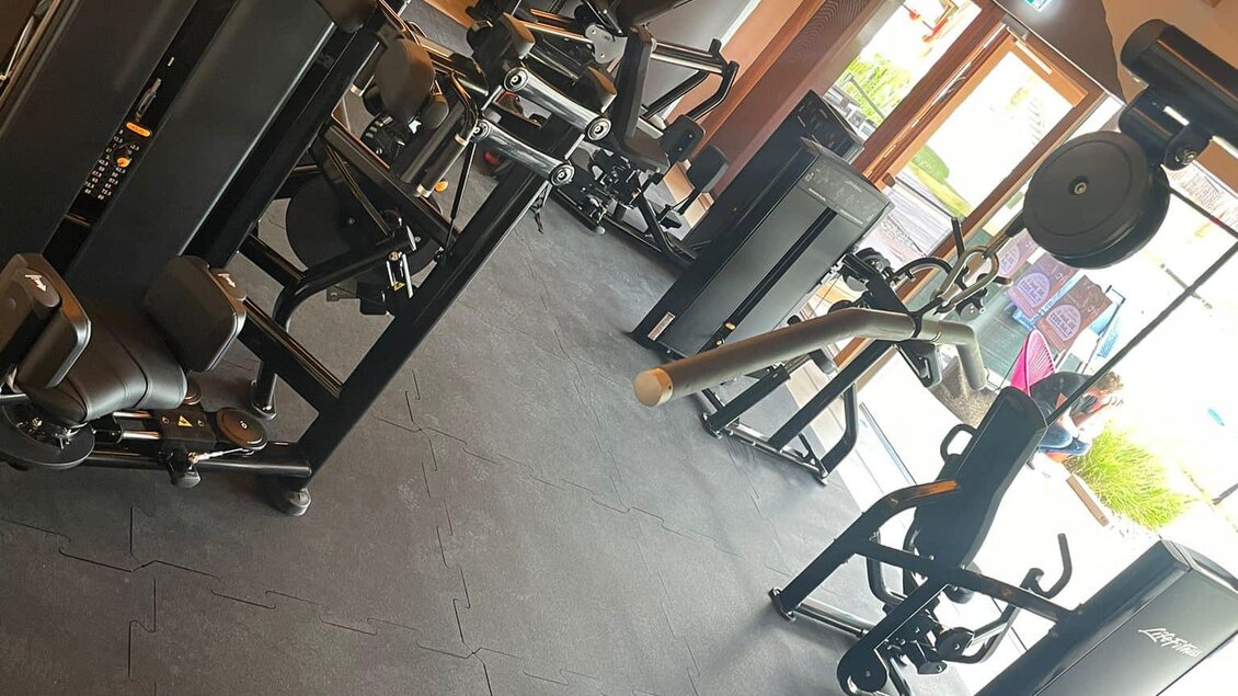 Ein modernes Fitnessstudio mit verschiedenen Trainingsgeräten. Der Raum ist hell und einladend, ideal für ein effektives Workout.