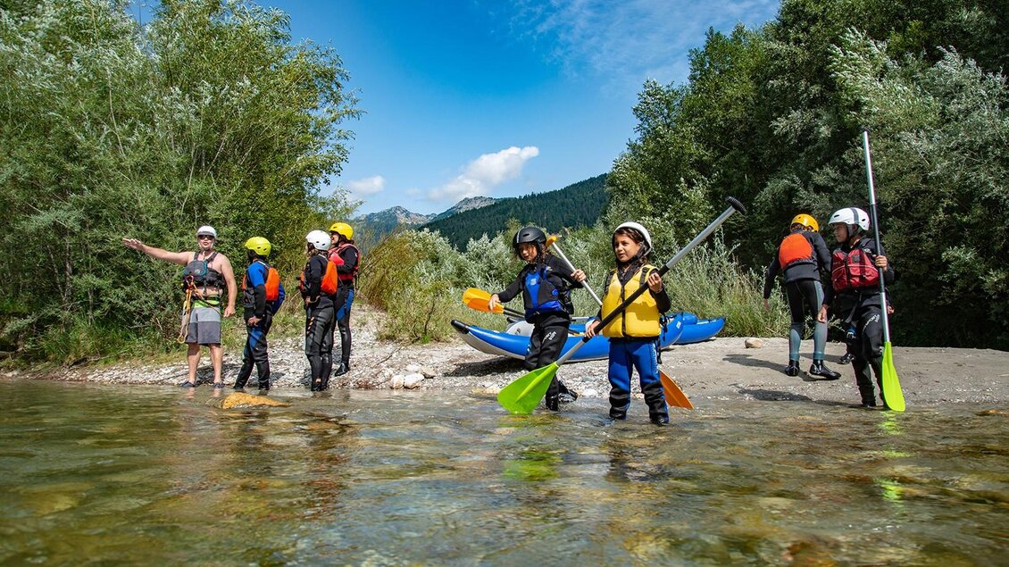 Eine Gruppe von Personen in Neoprenanzügen und Schwimmwesten steht am Ufer, bereit zum Kajakfahren. | © Kajaktiv
