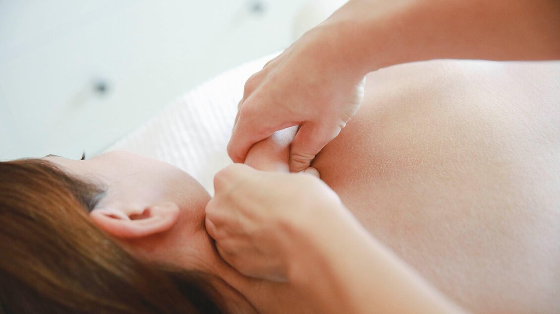 Eine Person erhält eine Massage im Nackenbereich. Die entspannende Atmosphäre ist deutlich zu spüren. | © Symbolfoto