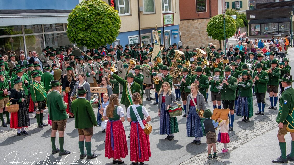 Eine begeisterte Menschenmenge feiert in traditioneller Tracht. Musikanten spielen und Kinder nehmen an dem fröhlichen Fest teil. | © fotobook