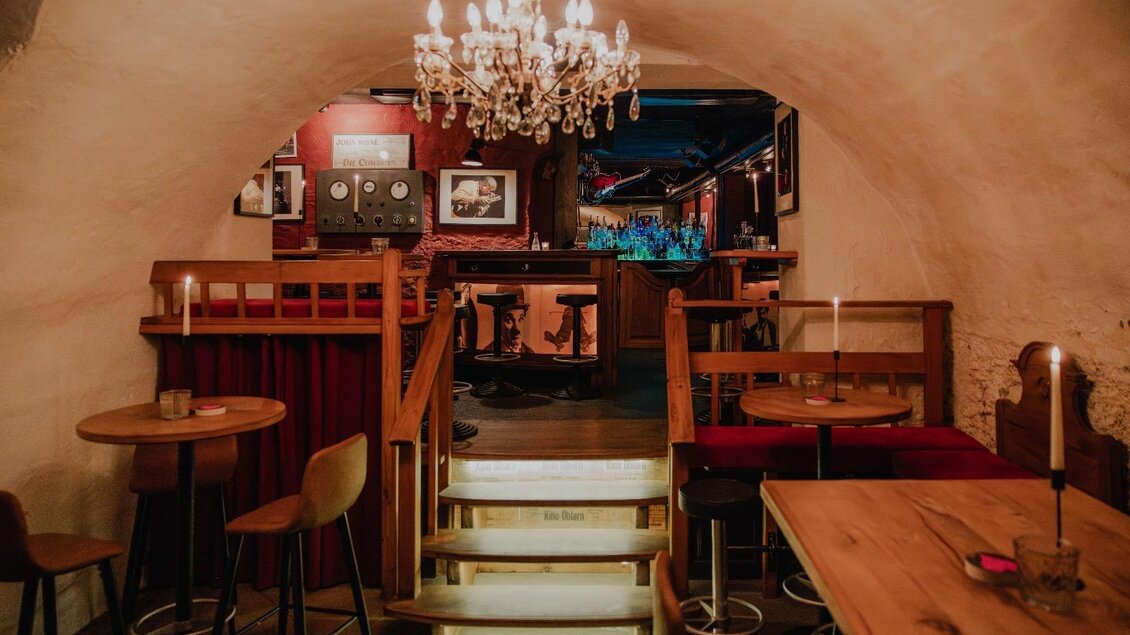 Ein gemütliches Restaurant mit einer warmen Atmosphäre. Der Raum ist mit einem Kronleuchter und stilvollen Möbeln dekoriert.