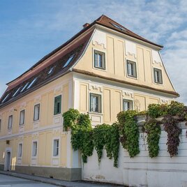 Ein schönes, historisches Haus mit gelber Fassade und grünen Pflanzen. Der Himmel ist klar und sorgt für eine angenehme Atmosphäre. | © Helmut Schweighofer