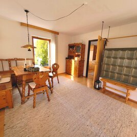 A cozy dining area with a wooden table and chairs. A large, bright room with a carpet and an attractive wall design.