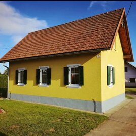 Ein kleines, gelbes Haus mit einem roten Dach und grünen Fensterläden. Es ist von einem gepflegten Rasen umgeben. | © Ferienhaus Raiter | Josef & Andreas Hödl