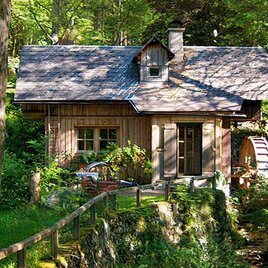 Ein charmantes Holzhaus umgeben von üppigem Grün. Ein kleiner Wasserfall und eine Holzbrücke schaffen eine idyllische Atmosphäre. | © Ingo Freese