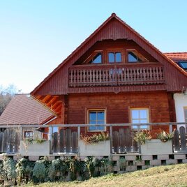 Ein charmantes Holzhaus mit einem Balkon und einer großen Terrasse. Die Umgebung ist von Natur und Wald umgeben. | © Maximilian Hackl