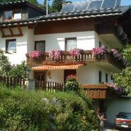 A charming multi-family house with blooming balcony plants. Surrounded by green scenery and sunshine.