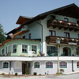 A charming building in alpine style with balconies and flower pots. Surrounded by green trees and a tranquil environment.