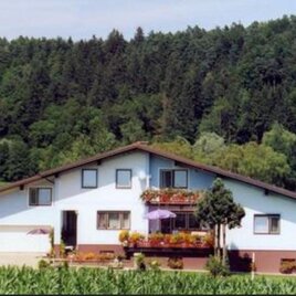 Ein hübsches Haus umgeben von grünen Feldern und Bäumen. Die Fassade ist hell und mit Blumen geschmückt. | © Gästehaus Stübler | Karoline & Rudolf Stübler