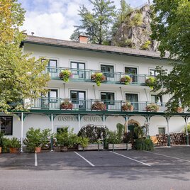 Ein charmantes Hotel mit mehreren Balkonen und Blumenkübeln. Es ist von Bäumen umgeben und bietet eine einladende Atmosphäre. | © 5komma5sinne