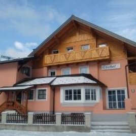 A beautiful house with wooden cladding and a balcony tower. The entrance is inviting and the building has a cozy atmosphere.