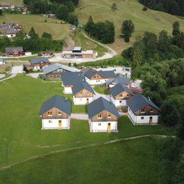 <p>Luftaufnahme der Hideaway Chalets Loser in Altaussee. Die sieben Ferienhäuser liegen am Fuße des Sandlings direkt beim Skigebiet Loser, im Hintergrund ist die Loser Panoramabahn zu sehen.</p> | © Aleida Albers