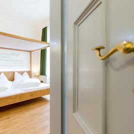 Ein einladendes Schlafzimmer mit einem gemütlichen Doppelbett und weißen Kissen. Der Raum wirkt hell und freundlich mit Holzfußboden und grünen Vorhängen. | © Harry Schiffer/Schiffer Photodisign