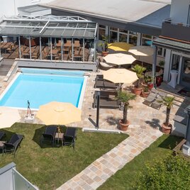 Ein schöner Außenbereich mit einem blauen Pool und Liegestühlen. Umbrella und Pflanzen schaffen eine einladende Atmosphäre.