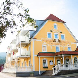Ein gelbes, stilvolles Gebäude mit mehreren Etagen und Balkonen. Es hat eine einladende Fassade und liegt in einer ruhigen Umgebung. | © Joglland Hotel