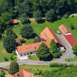 Ein großes Grundstück mit mehreren Gebäuden und vielen Bäumen. Der Garten ist grün und gepflegt, umgeben von einem ruhigen Weg. | © gartner