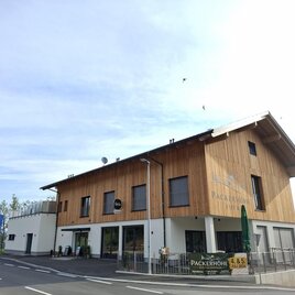 Außenansicht des Hotels Packerhöhe in Hirschegg-Pack mit Holzfassade, Eingangsbereich und Terrasse an der Straße. | © Region Graz_Astrid Lackner