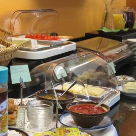 Ein reichhaltiges Frühstücksbuffet mit frischen Brötchen, Marmelade und verschiedenen Aufstrichen. Dazu gehören auch Obst, Säfte und eine Auswahl an Getränken. | © Pension Maria