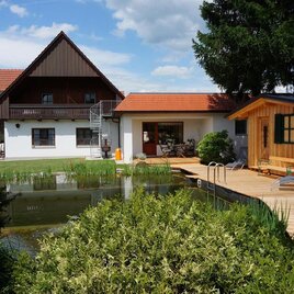 Ein schönes Haus mit einem großen Garten und einem Teich. Die Terrasse und die Holzsauna verleihen der Umgebung einen einladenden Charakter. | © Pension Wolkenreich | Klaus Kovacs