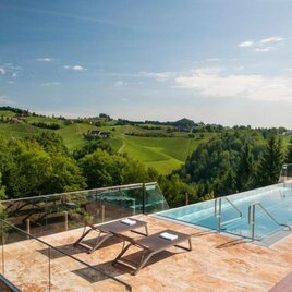 Ein moderner Pool mit Blick auf grüne Hügel und Wälder. Die entspannende Atmosphäre lädt zum Verweilen ein. | © Weingut Sabathihof | Fam. Dillinger