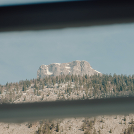 Ein Blick durch ein Fenster auf einen beeindruckenden Berg. Im Vordergrund sind Bäume und eine schöne Landschaft sichtbar. | © Sieglgut