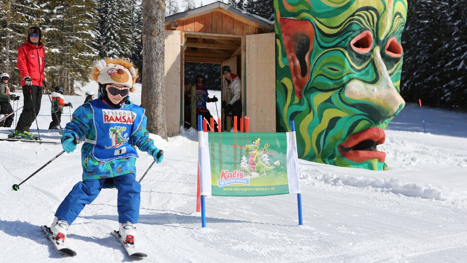 Kind am Skifahren mit kunstvollem Steinkopf im Hintergrund.